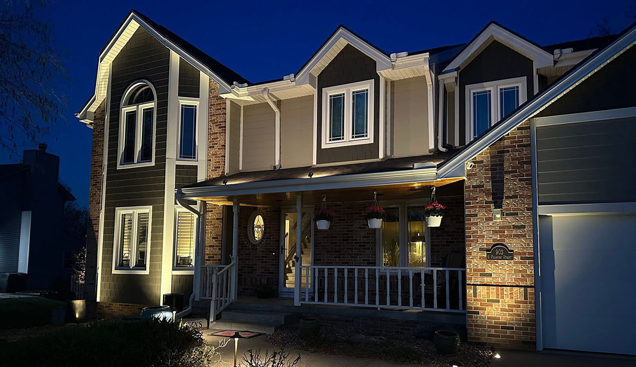 Front porch and exterior walls lit with precision through expert lighting maintenance for a well-balanced nighttime glow.