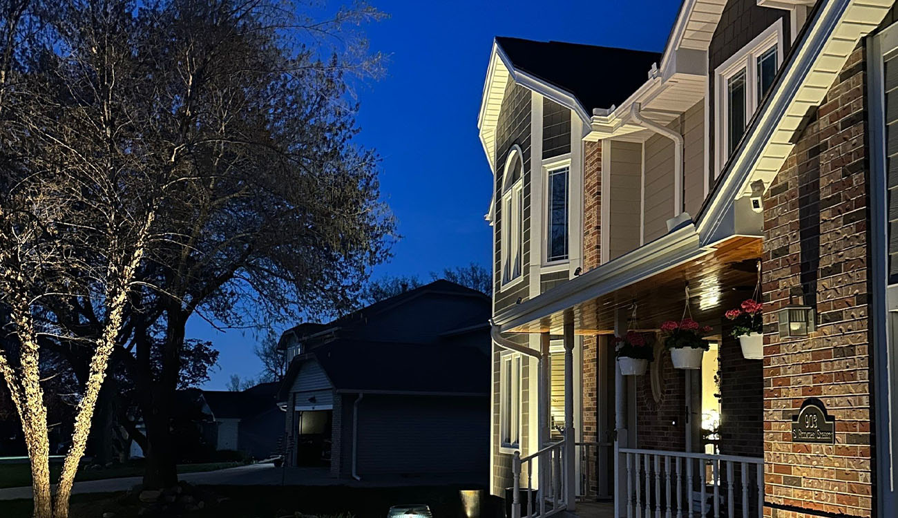 Side view of home lighting maintenance highlighting trees and architectural details for consistent brightness and safety.