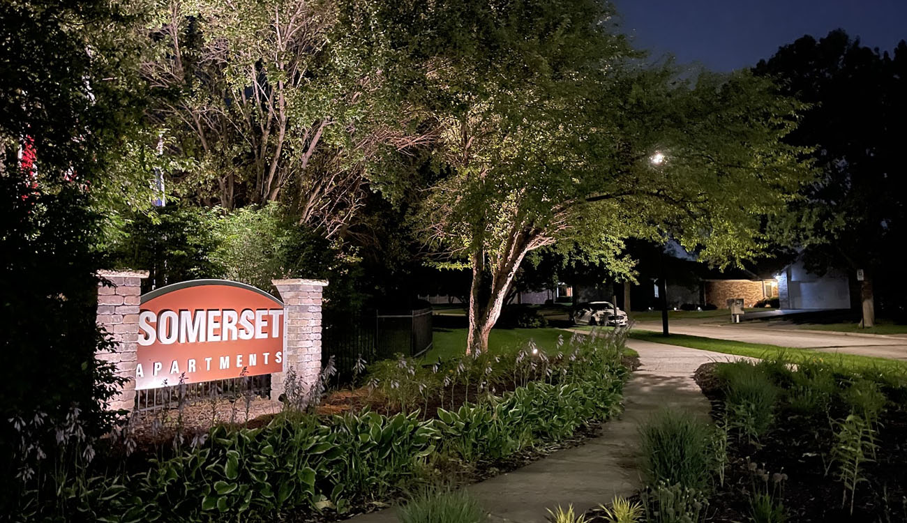 Apartment community entrance sign lit with commercial outdoor lighting solutions to improve safety and curb appeal.
