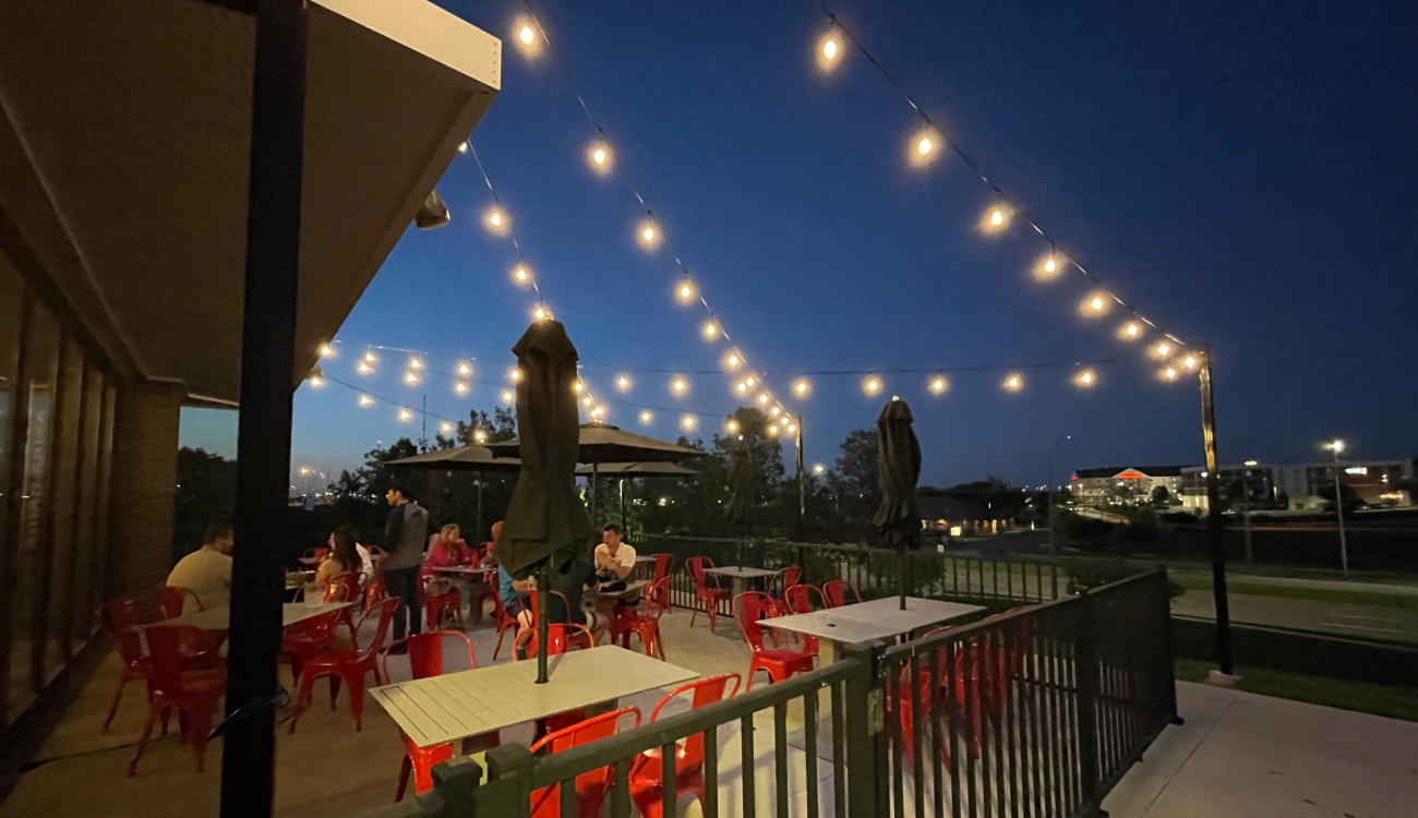 Outdoor string lights installed over a backyard patio