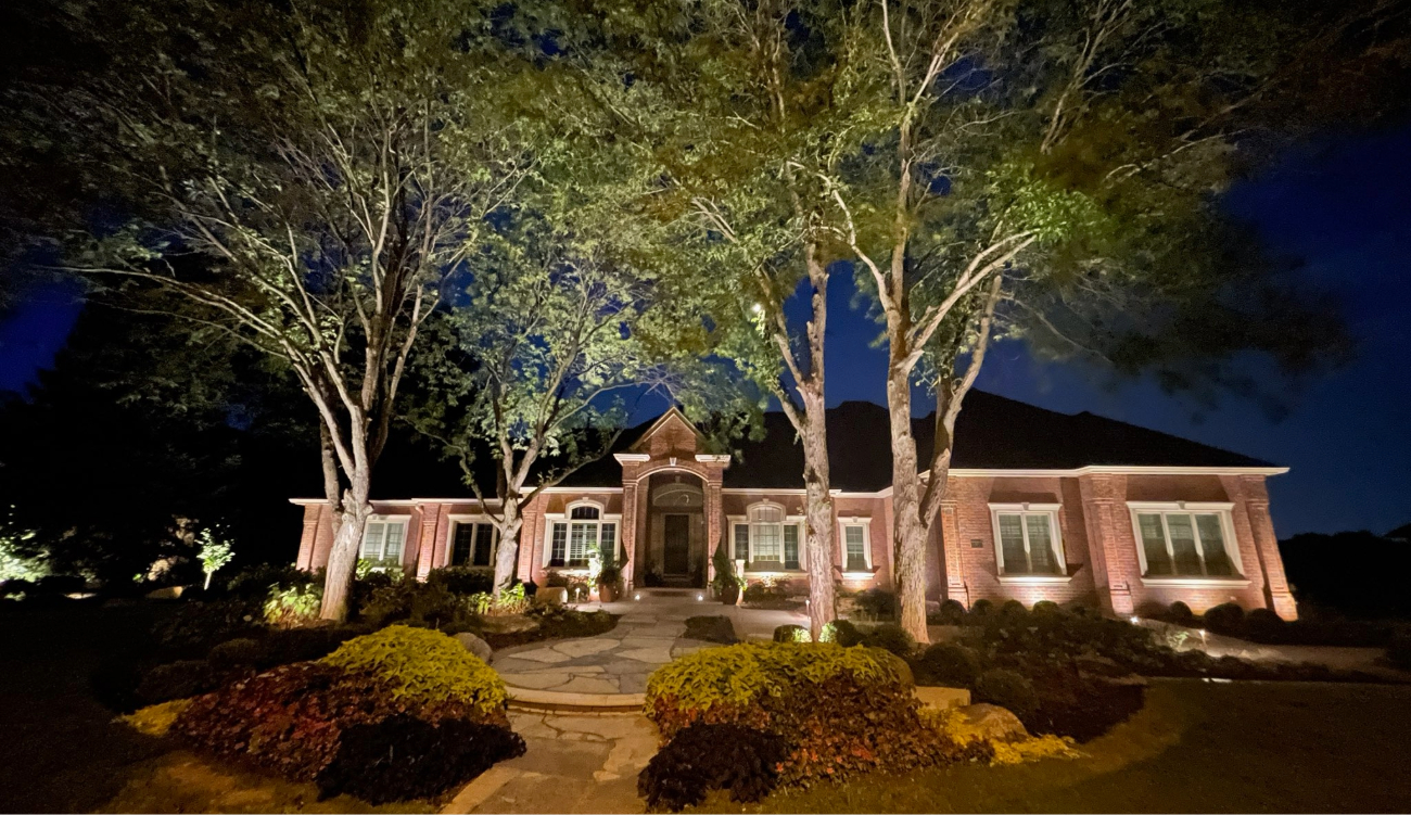 Upward lighting on a brick exterior following a custom landscape lighting installation by experts.