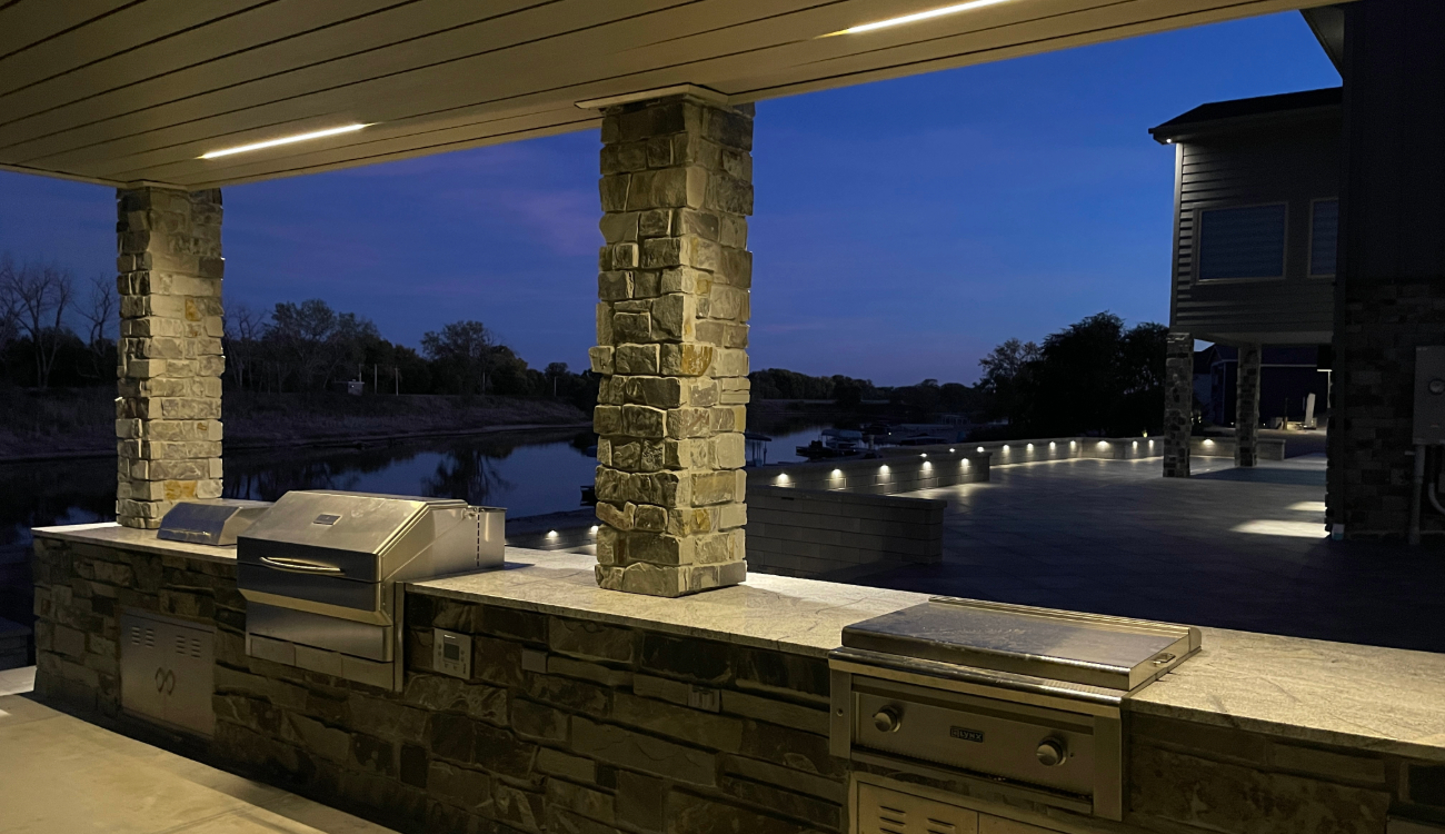 Modern outdoor kitchen featuring professional outdoor led lighting under the bar and ceiling.