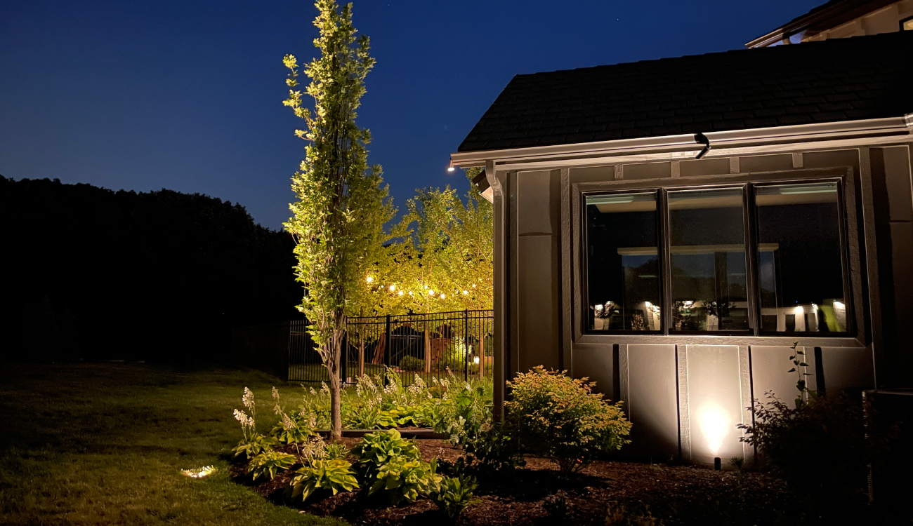 Beautifully lit garden and trees at dusk. Enhance your curb appeal with our professional landscape lighting repair and maintenance services for Midwest landscapes.