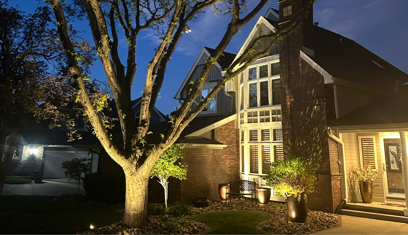 A tall brick home featuring professional outdoor light fixtures that highlight the front entrance.